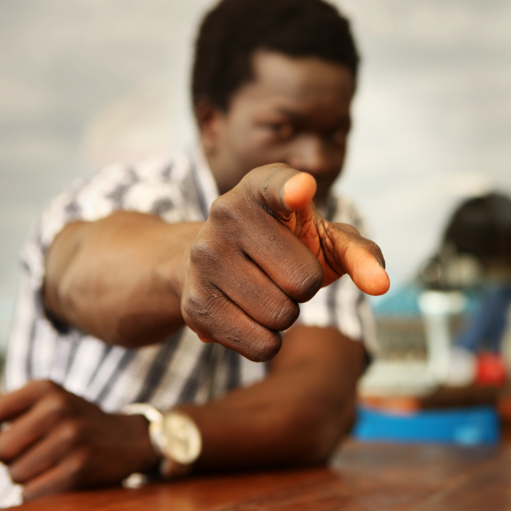 a man pointing at the camera with the focus being on his hand
